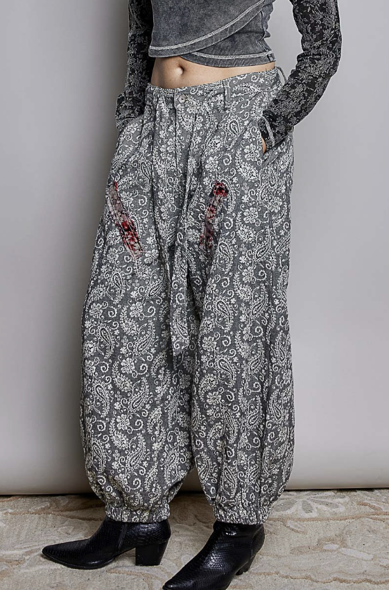 Woman wearing black paisley pants on plain background