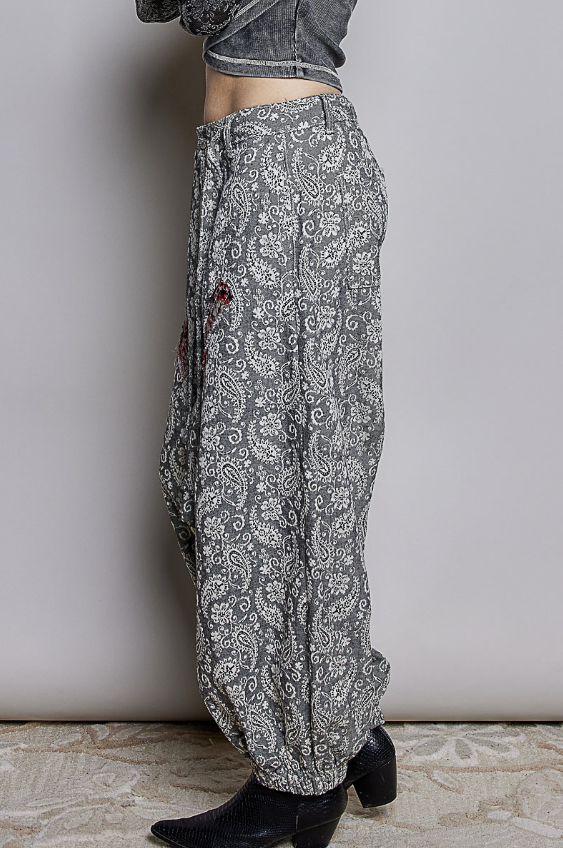 Woman wearing black paisley pants on plain background