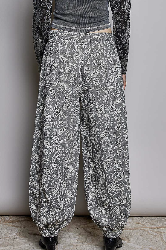 Woman wearing black paisley pants on plain background