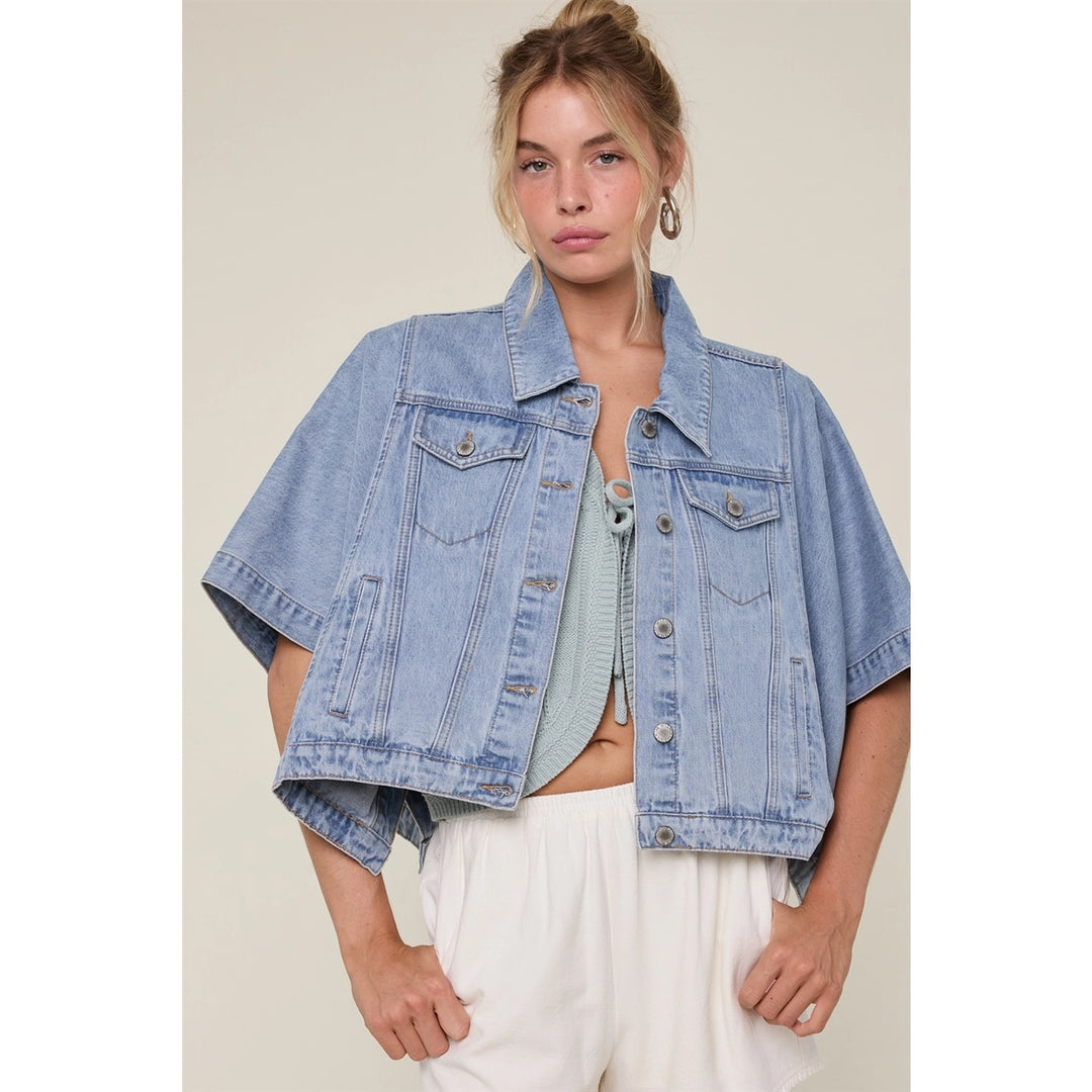Woman wearing denim cap jacket with white pants on plain background