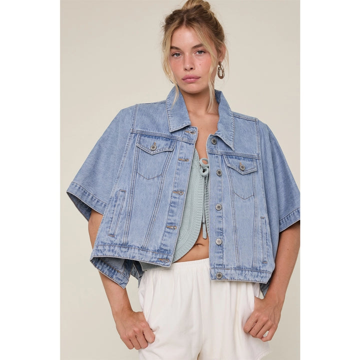 Woman wearing denim cap jacket with white pants on plain background