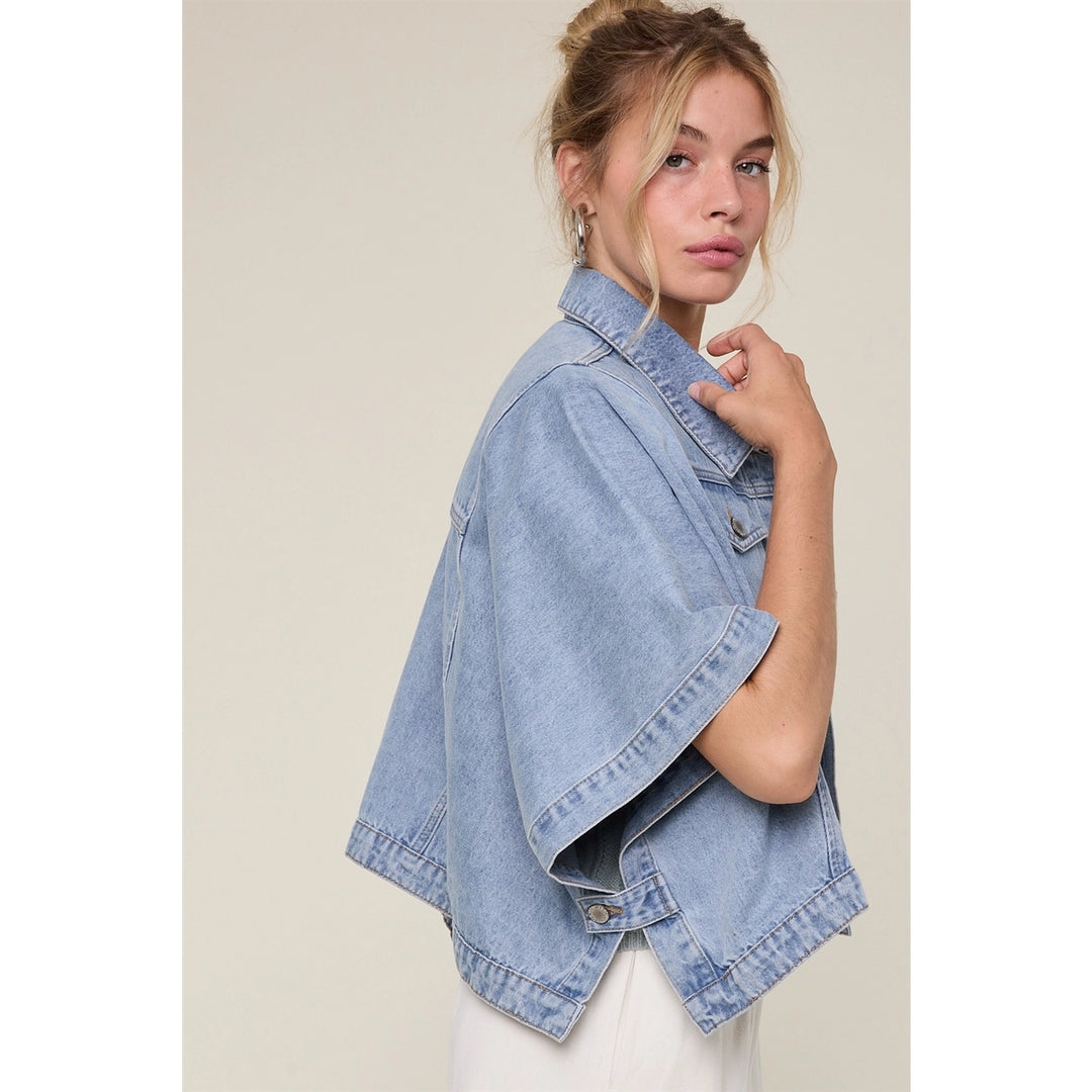 Woman wearing denim cape jacket on plain background