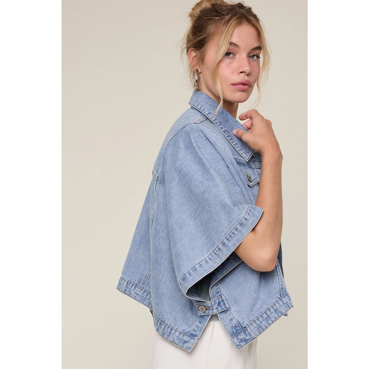 Woman wearing denim cape jacket on plain background
