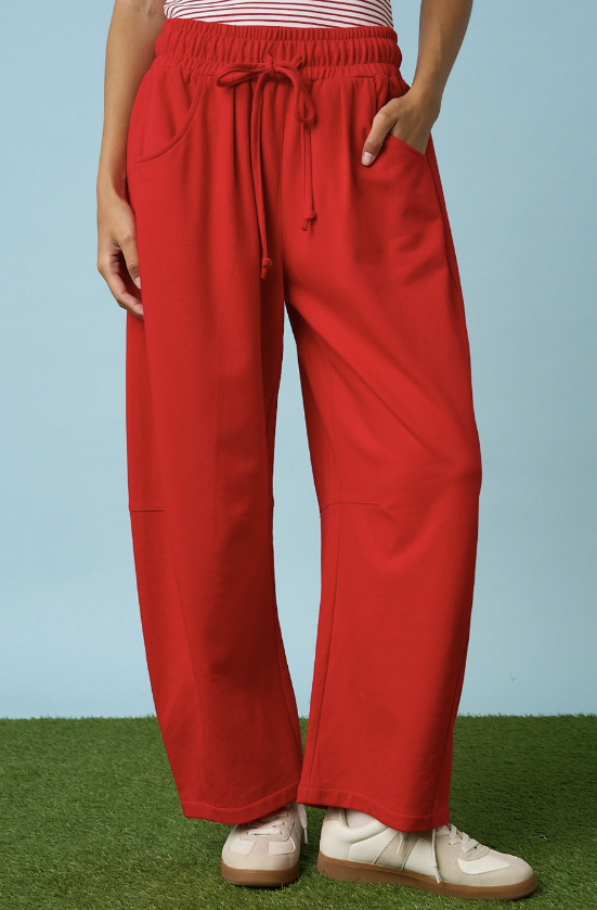 Woman wearing red sweatpants on blue background with grass