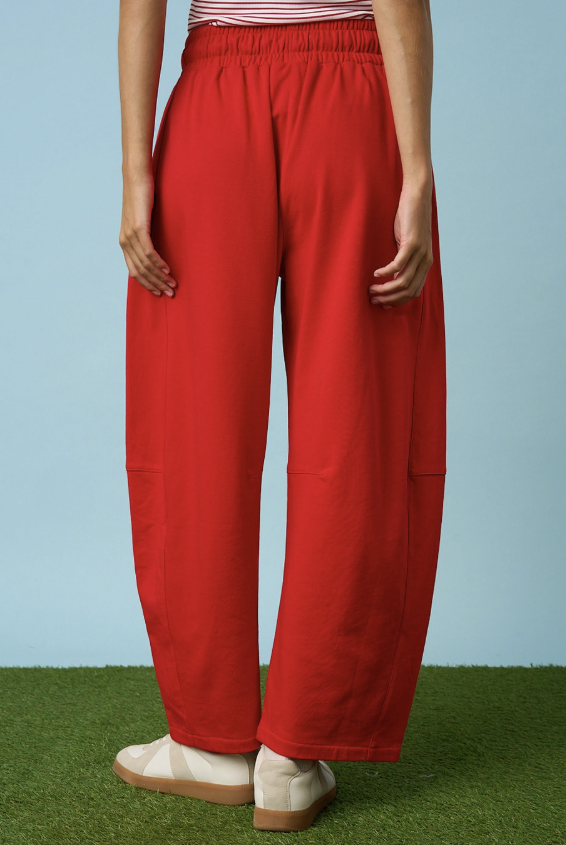 Woman wearing red sweatpants on blue background and grass floor