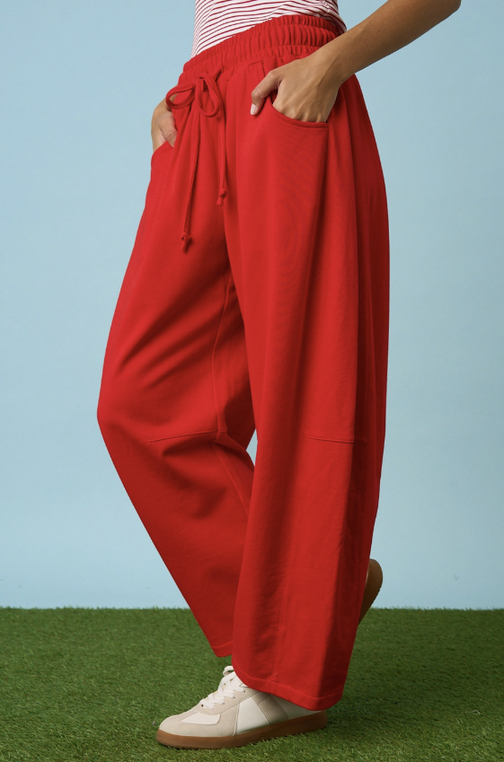 Woman wearing red sweatpants on blue background and grass floor