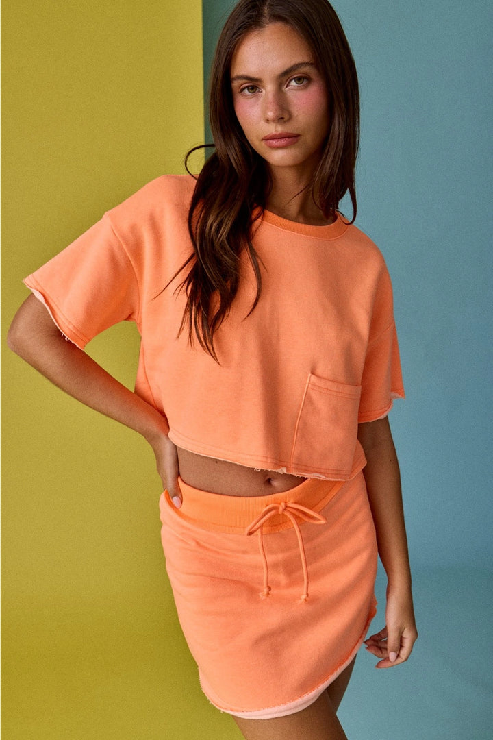 Woman wearing an orange outfit against a multicolored background