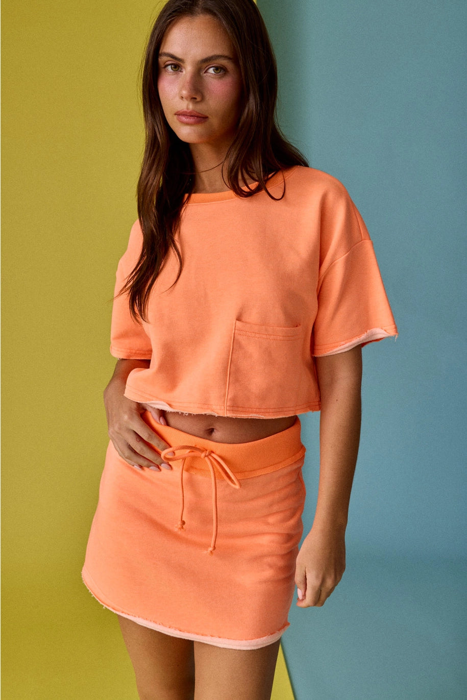 Woman wearing an orange outfit against a multicolored background