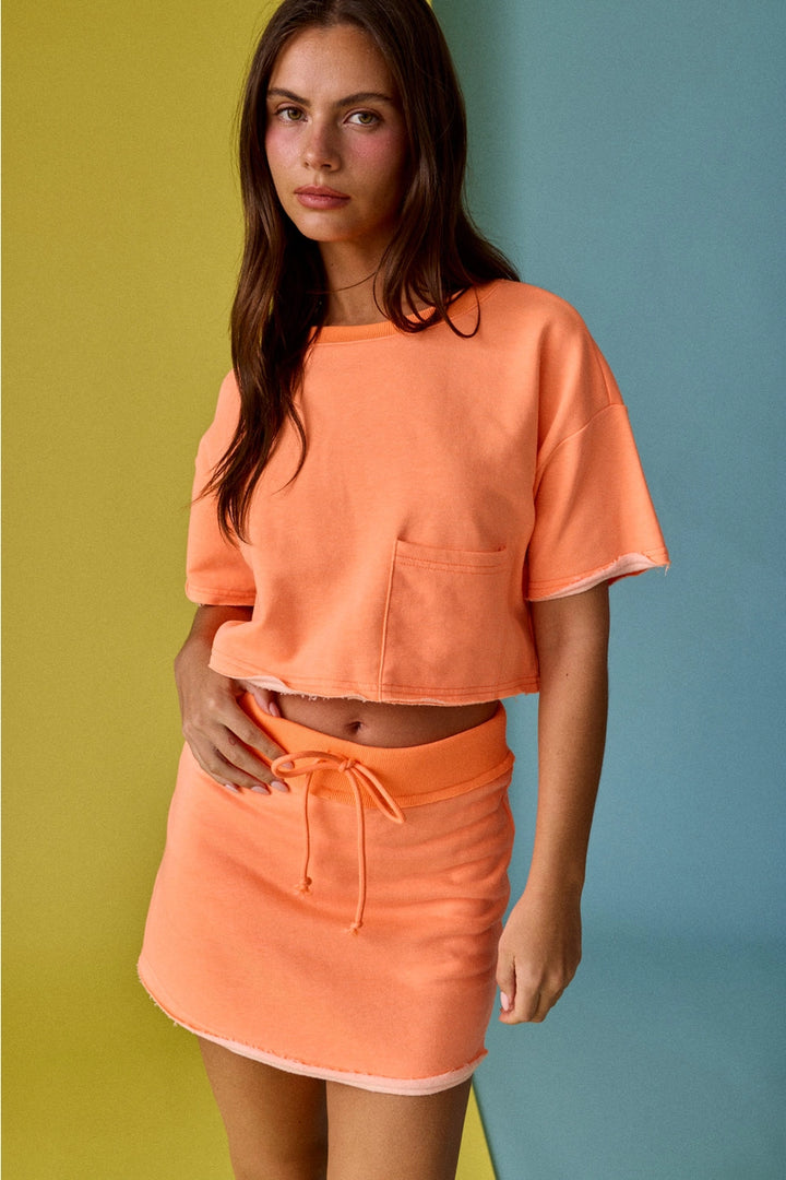 Woman wearing an orange outfit against a multicolored background