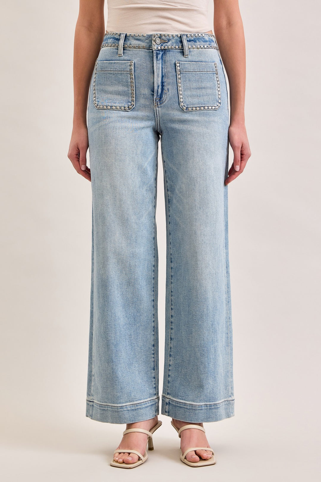 Light blue jeans worn by a person on a beige background