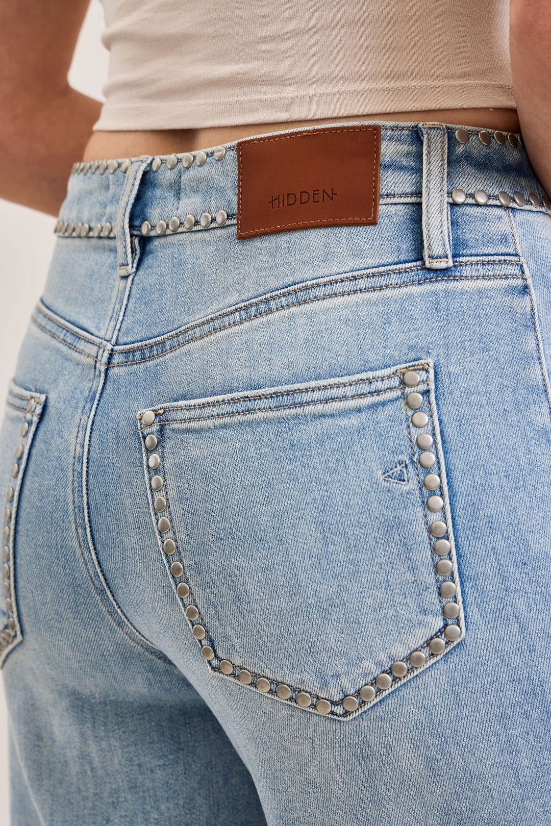 Close-up of light blue jeans with a brown belt and &