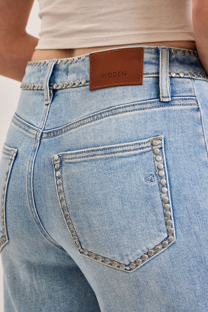 Close-up of light blue jeans with a brown belt and &