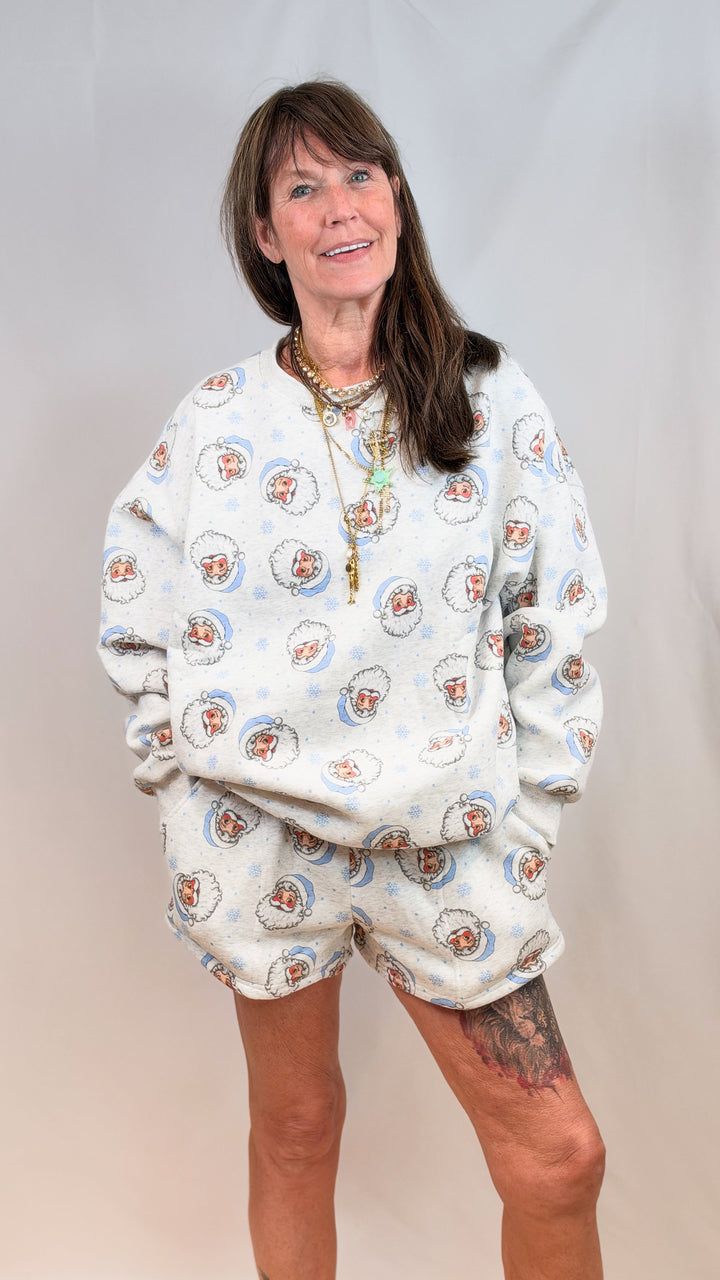 Woman wearing matching grey set with vintage blue santa faces on plain background