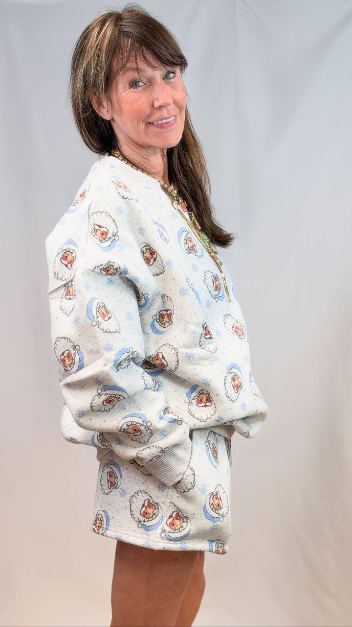 Woman wearing matching grey set with blue vintage santa faces on plain background