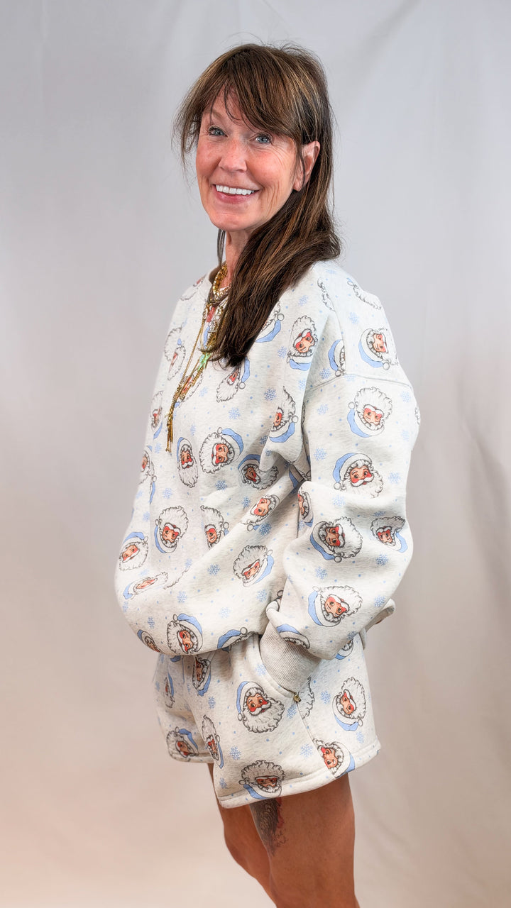 Woman wearing matching grey set with blue vintage santa faces on plain background