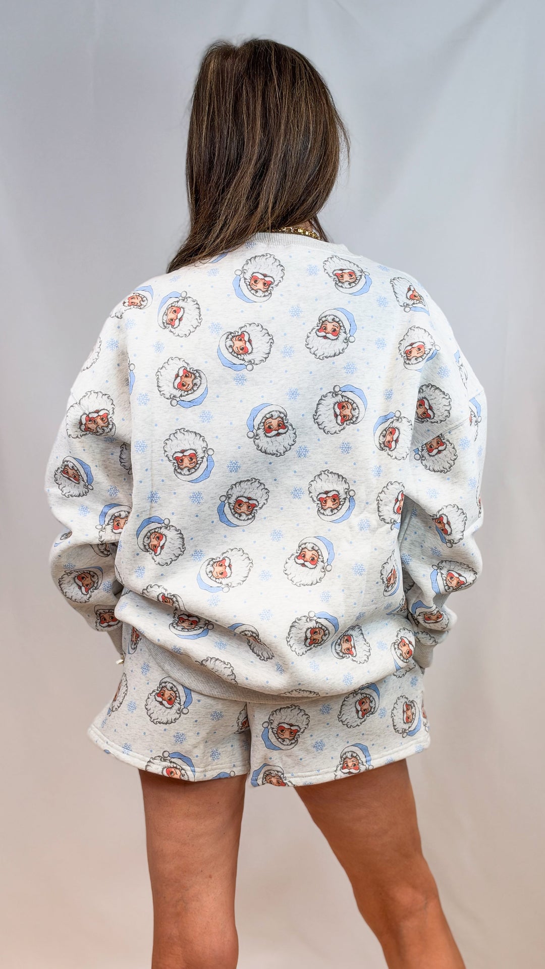 Woman shown from back wearing matching grey set with vintage blue santa faces on plain background