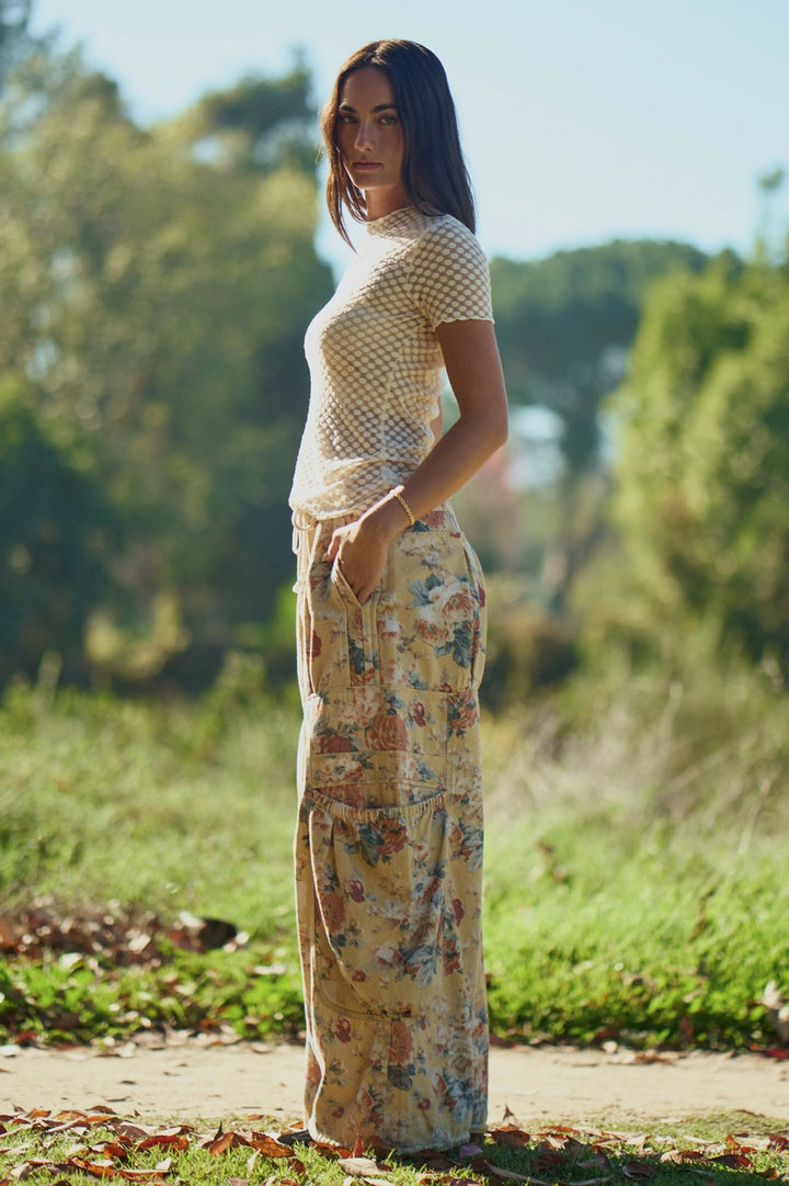 Woman wearing patterned pants standing in a natural setting with trees and grass.