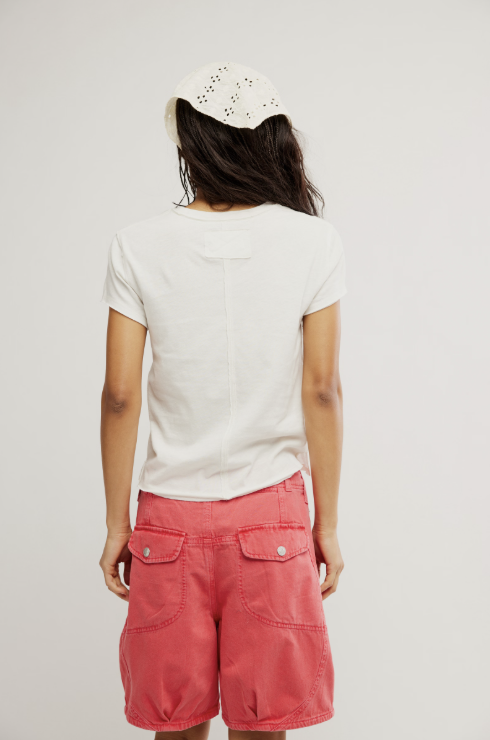 Back of woman wearing white tee and red shorts on white background