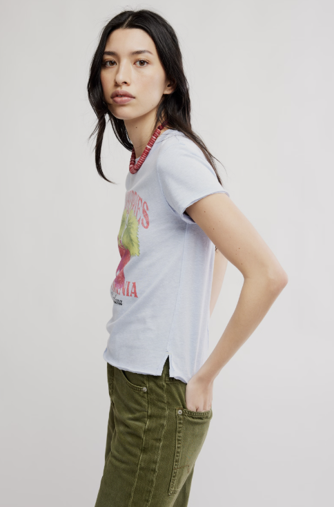 Woman wearing graphic tee with strawberries and green pants on white background