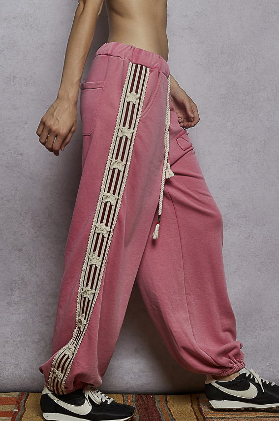 Woman wearing pink sweats with red ribbon detail and stars on plain background