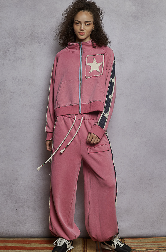 Woman wearing pink sweatsuit on plain background