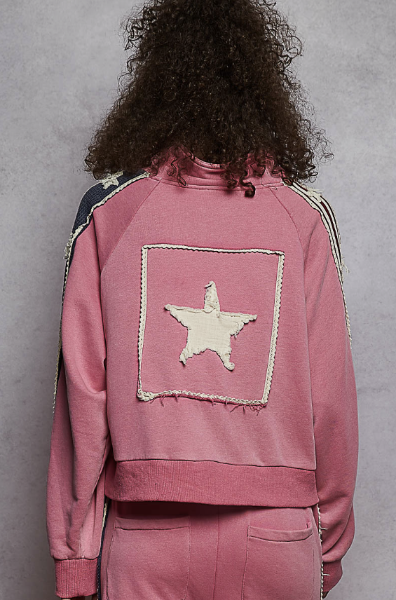 Woman wearing pink sweat suit with star on plain background