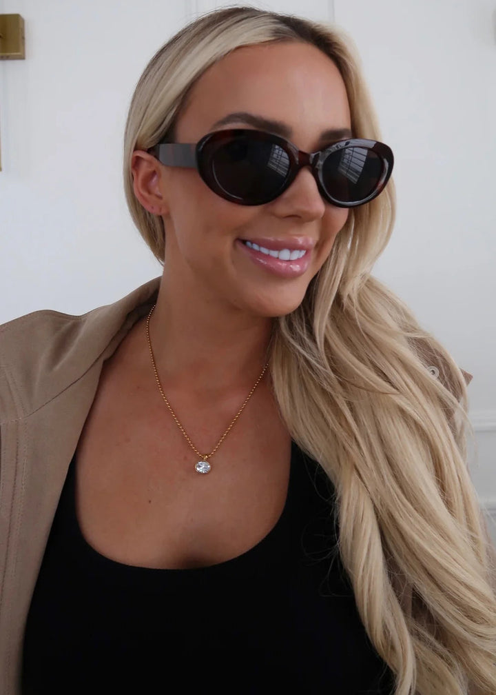 Woman wearing sunglasses with a neutral background