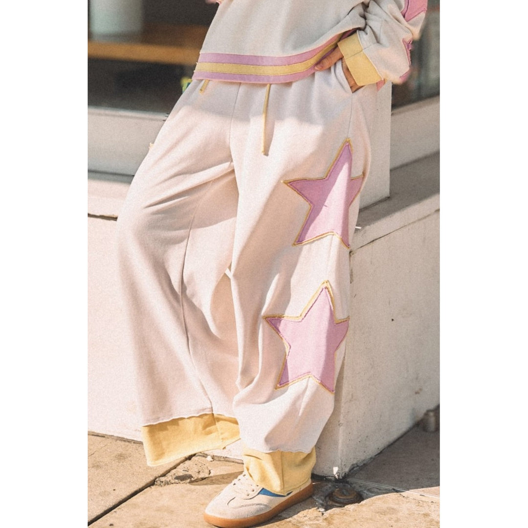 Person wearing white sweatpants with pink and yellow star details