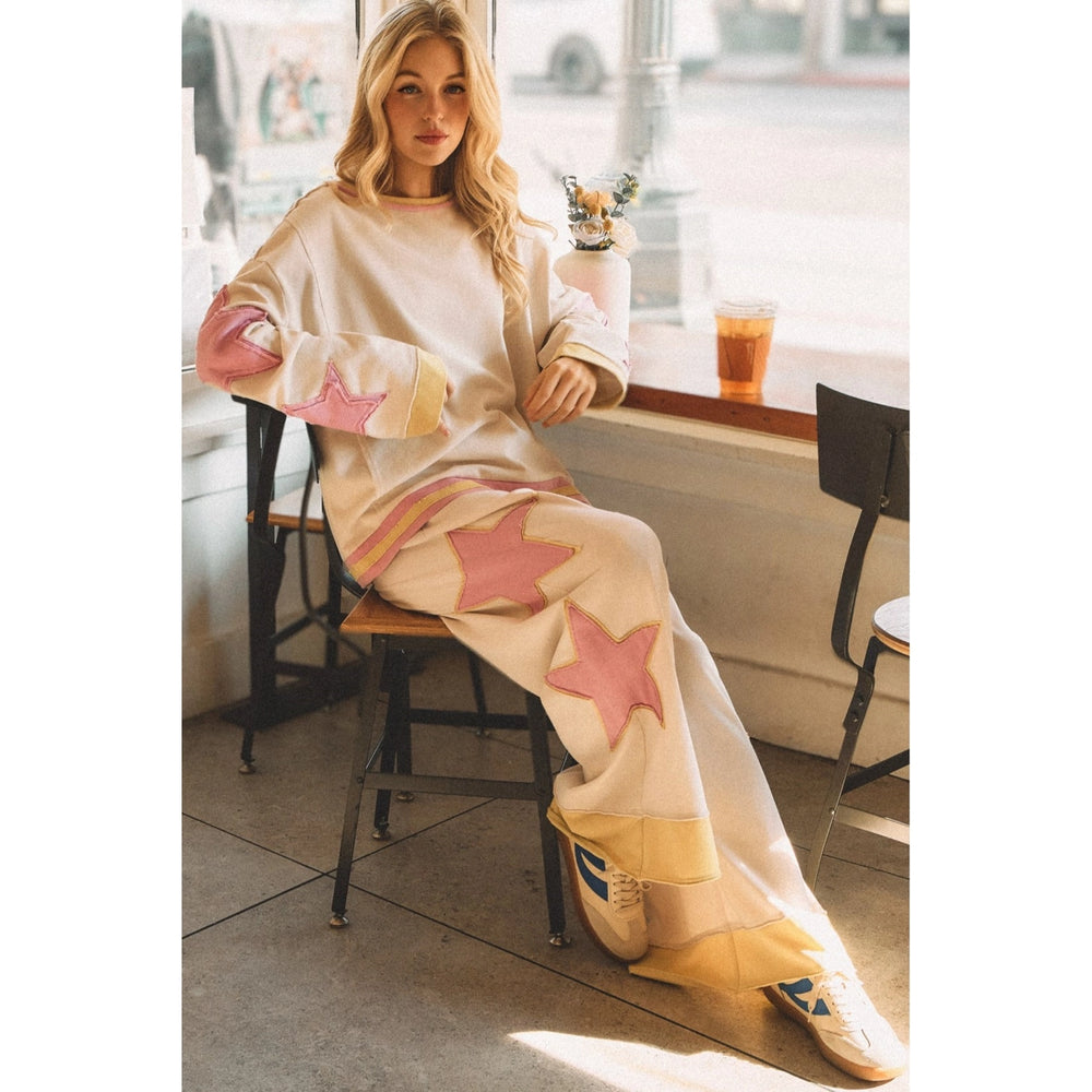 Woman wearing white sweatpants with pink and yellow star details in coffee shop