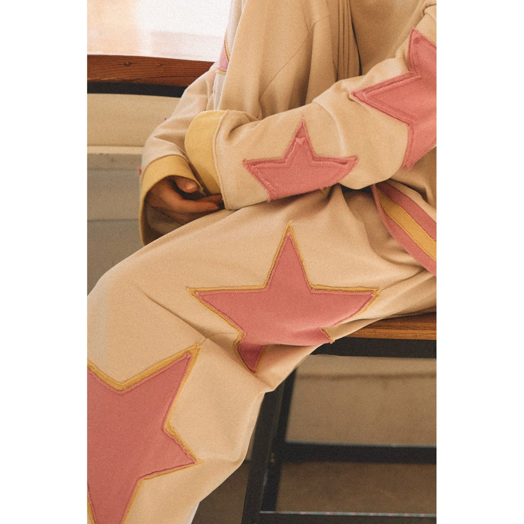 Person wearing white sweatpants with pink and yellow star details