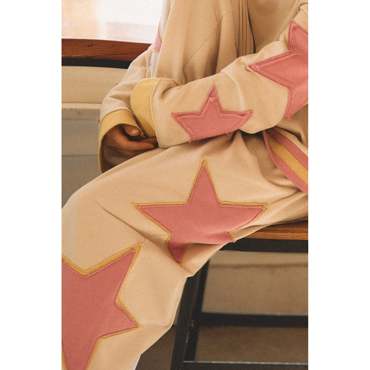 Person wearing white sweatpants with pink and yellow star details