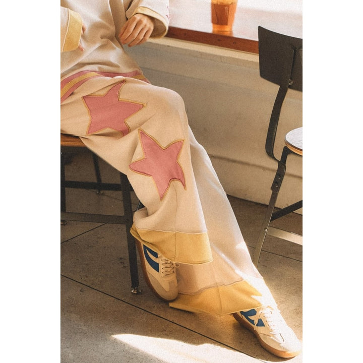 Person wearing white sweatpants with pink and yellow star details