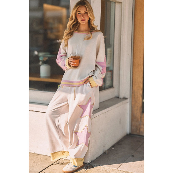 Person wearing white sweatpants with pink and yellow star details outdoors