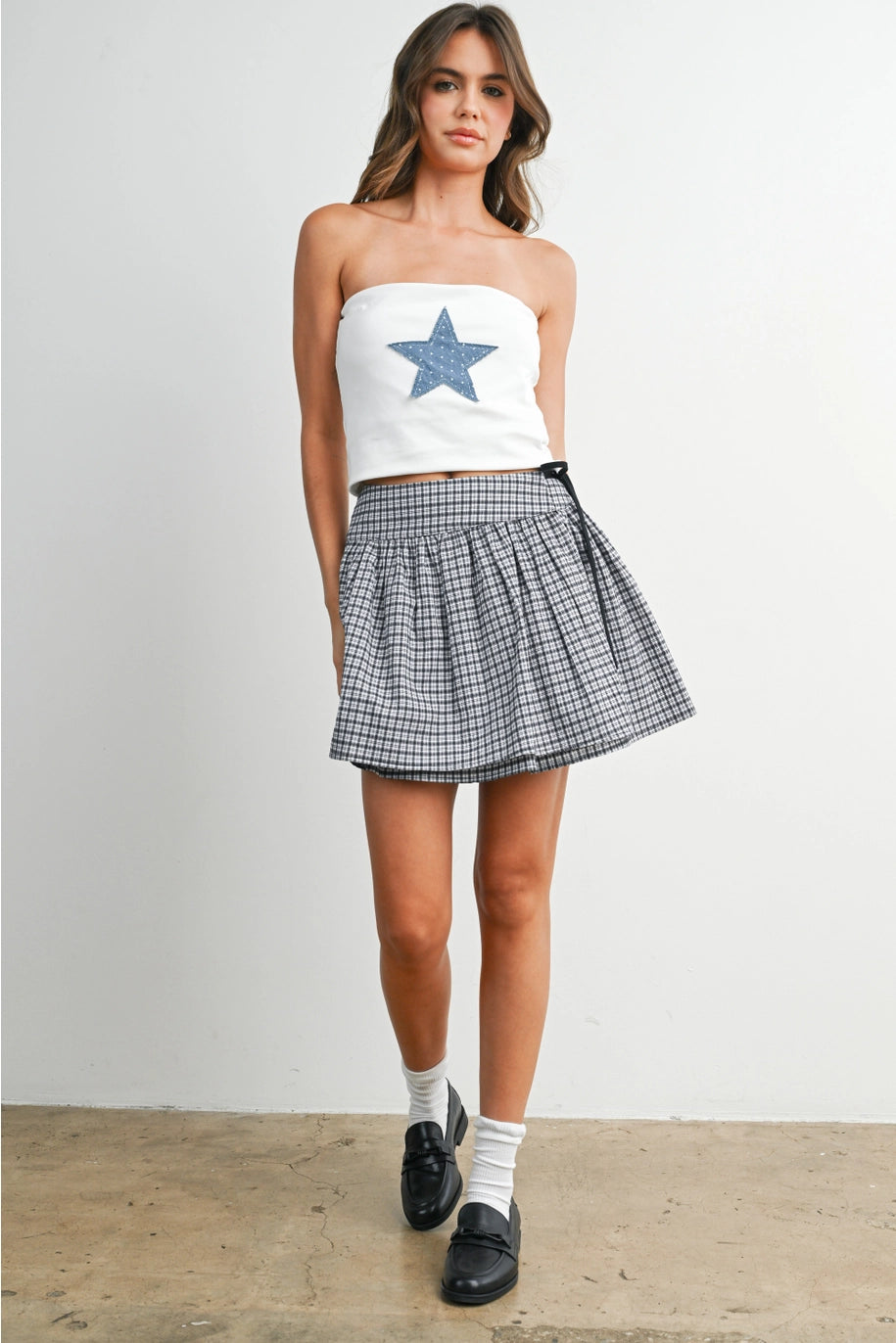 Woman wearing white tube top with blue star and skirt on white background