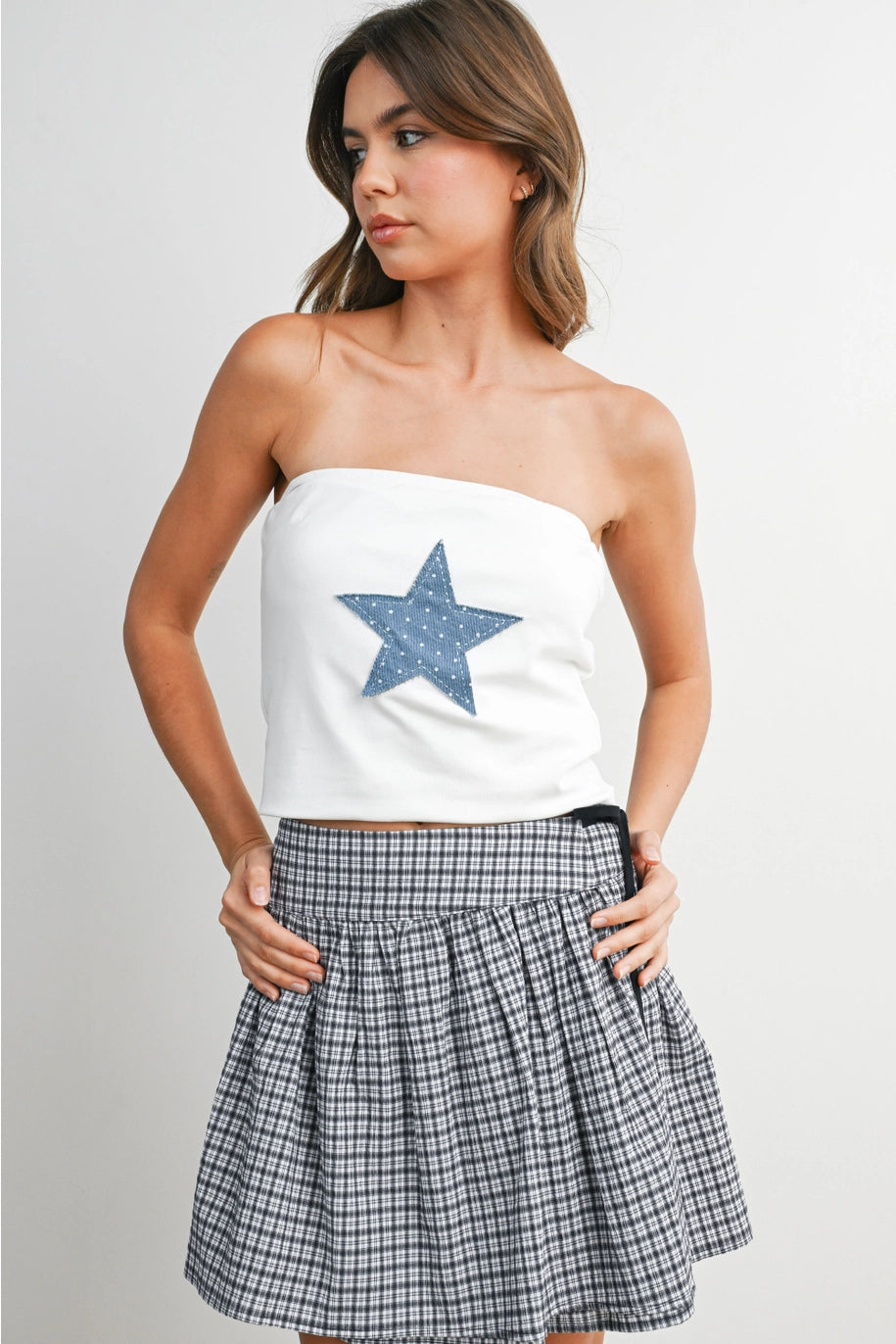 Woman wearing white tube top with blue star and skirt on white background