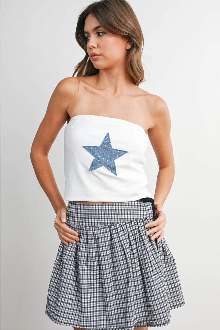 Woman wearing white tube top with blue star and skirt on white background
