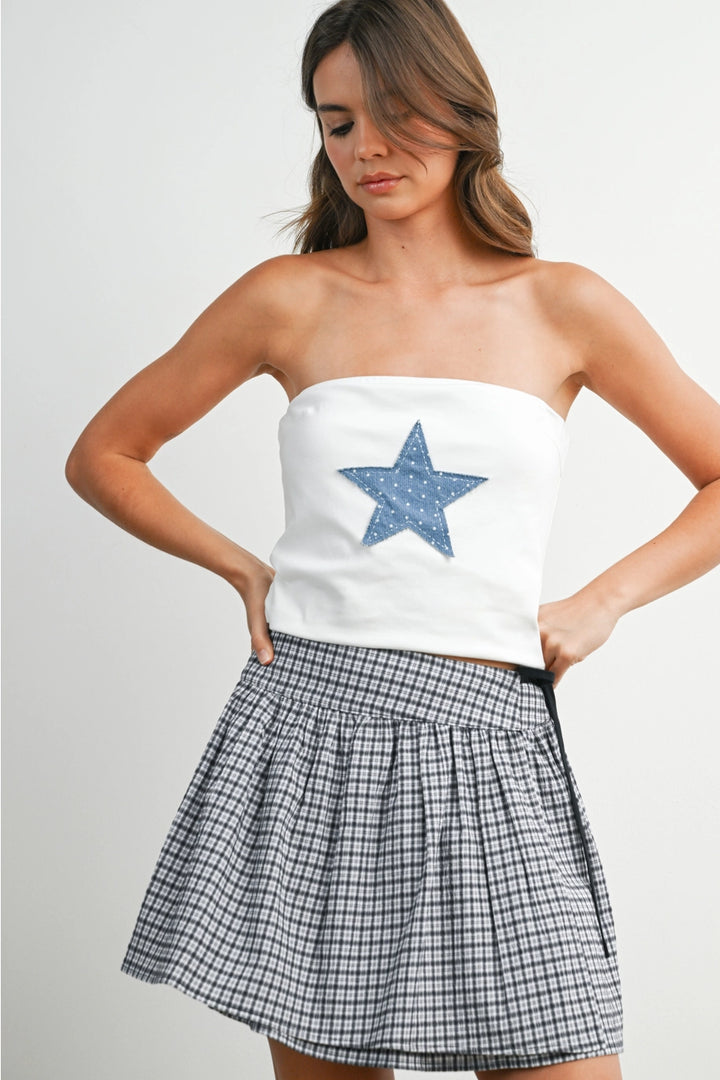Woman wearing white tube top with blue star and skirt on white background