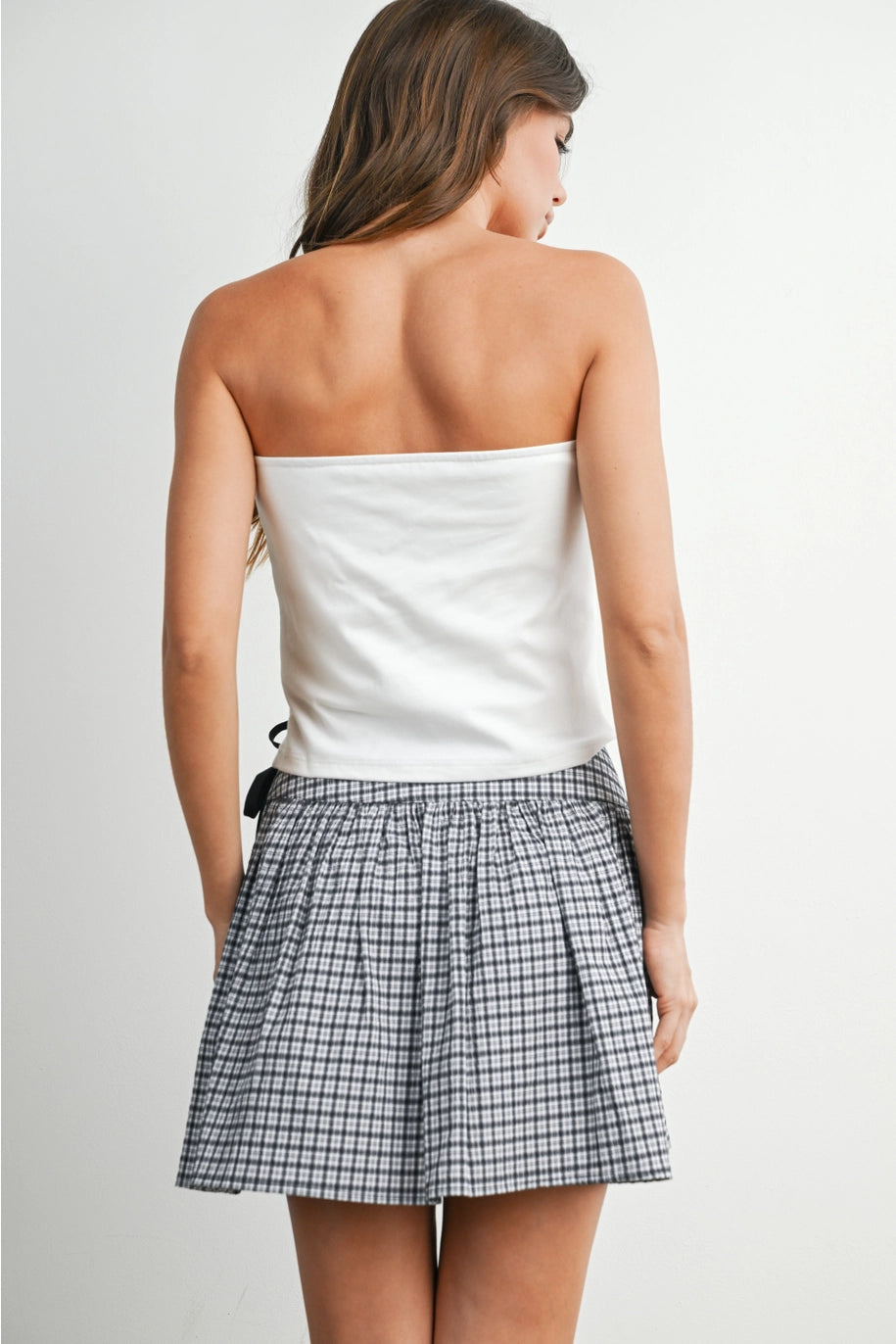 Back of woman wearing white tube top and skirt on white background