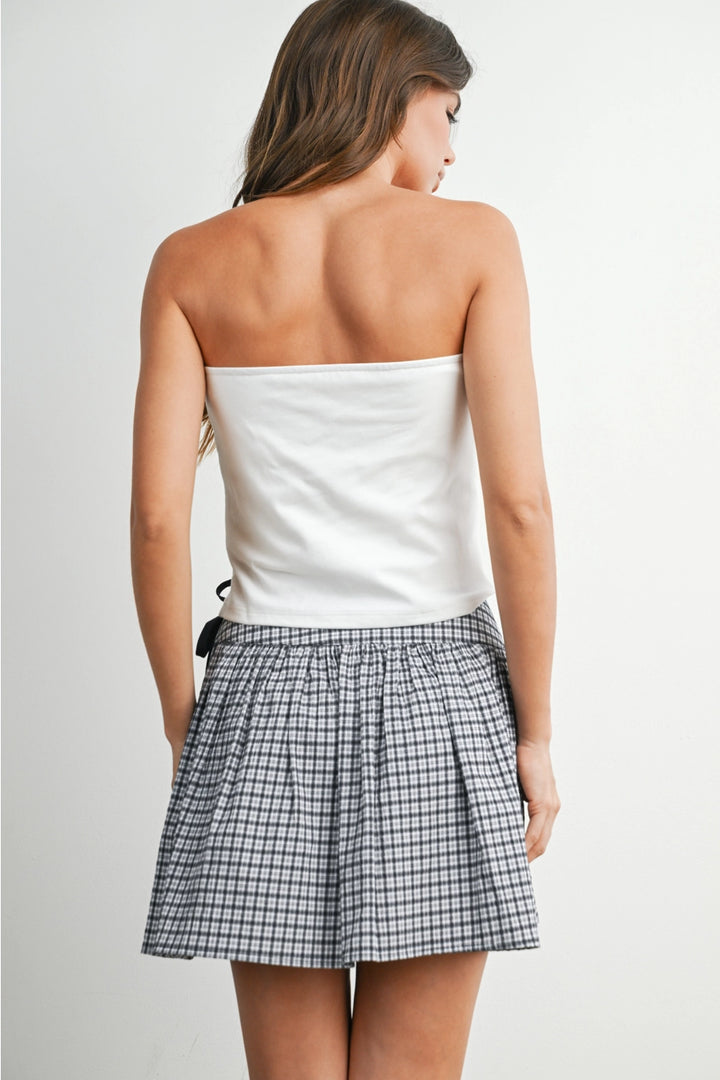 Back of woman wearing white tube top and skirt on white background