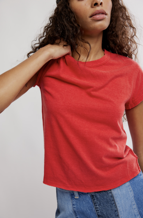 Person wearing a red t-shirt and blue jeans against a plain background