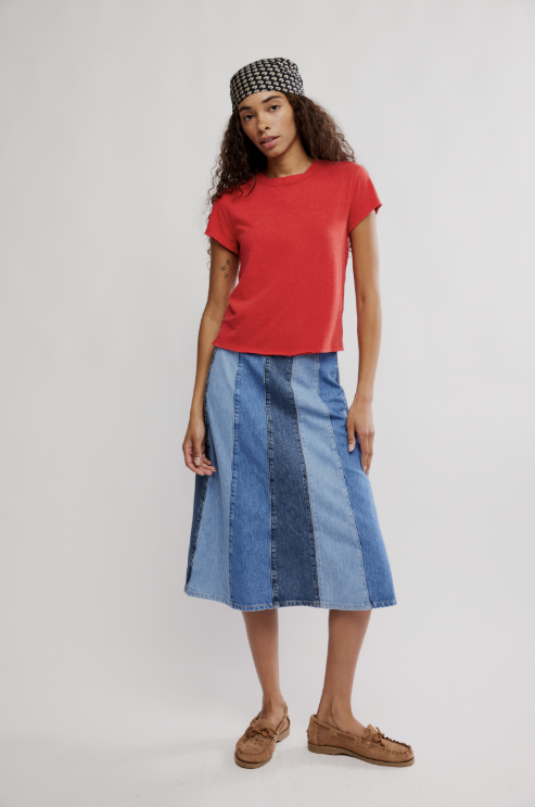 Woman wearing a red top and blue patchwork skirt on a white background