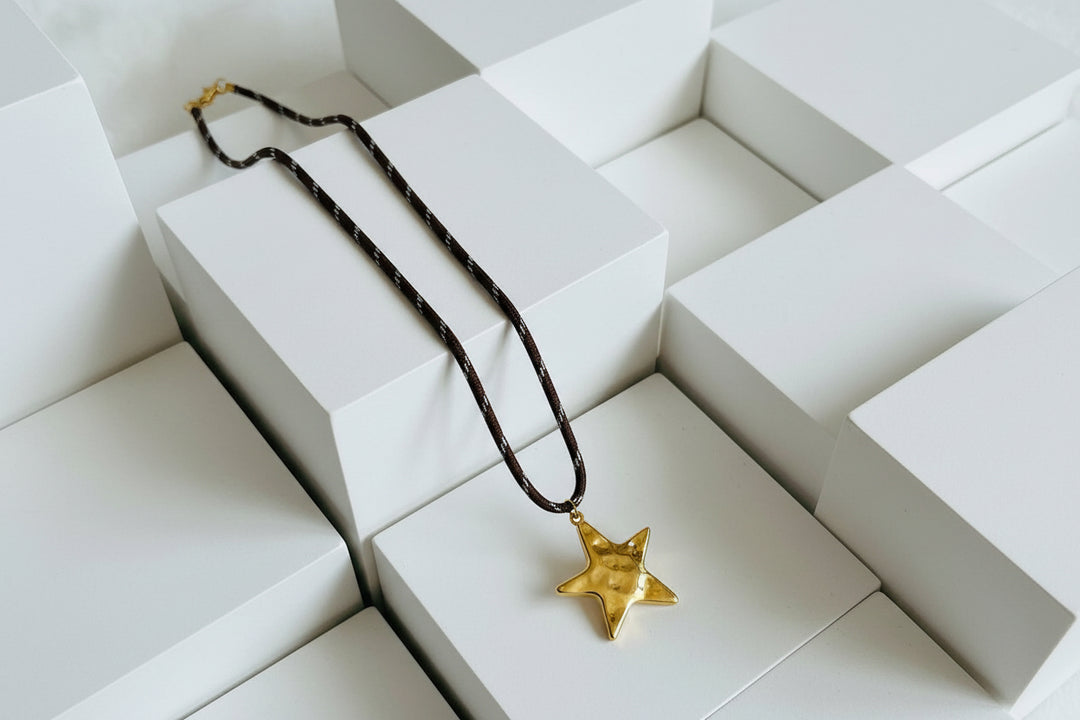 Star-shaped pendant on a brown cord against a white background