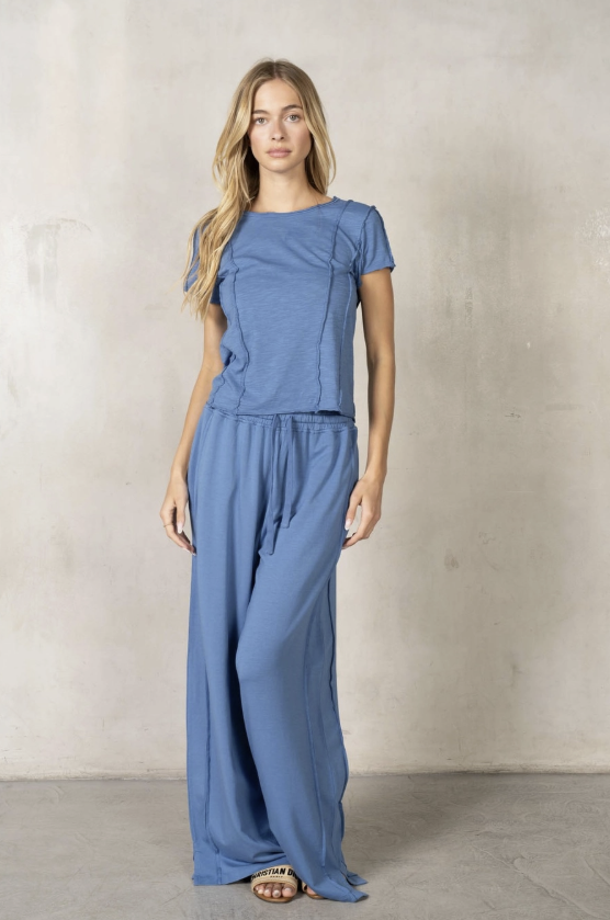 Woman wearing a blue jumpsuit against a plain background