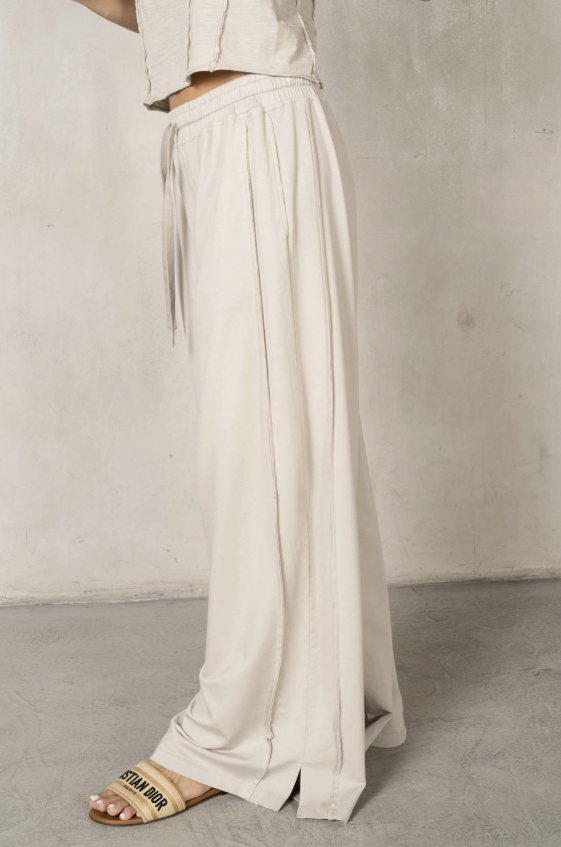 Person wearing white wide-leg pants with a neutral background