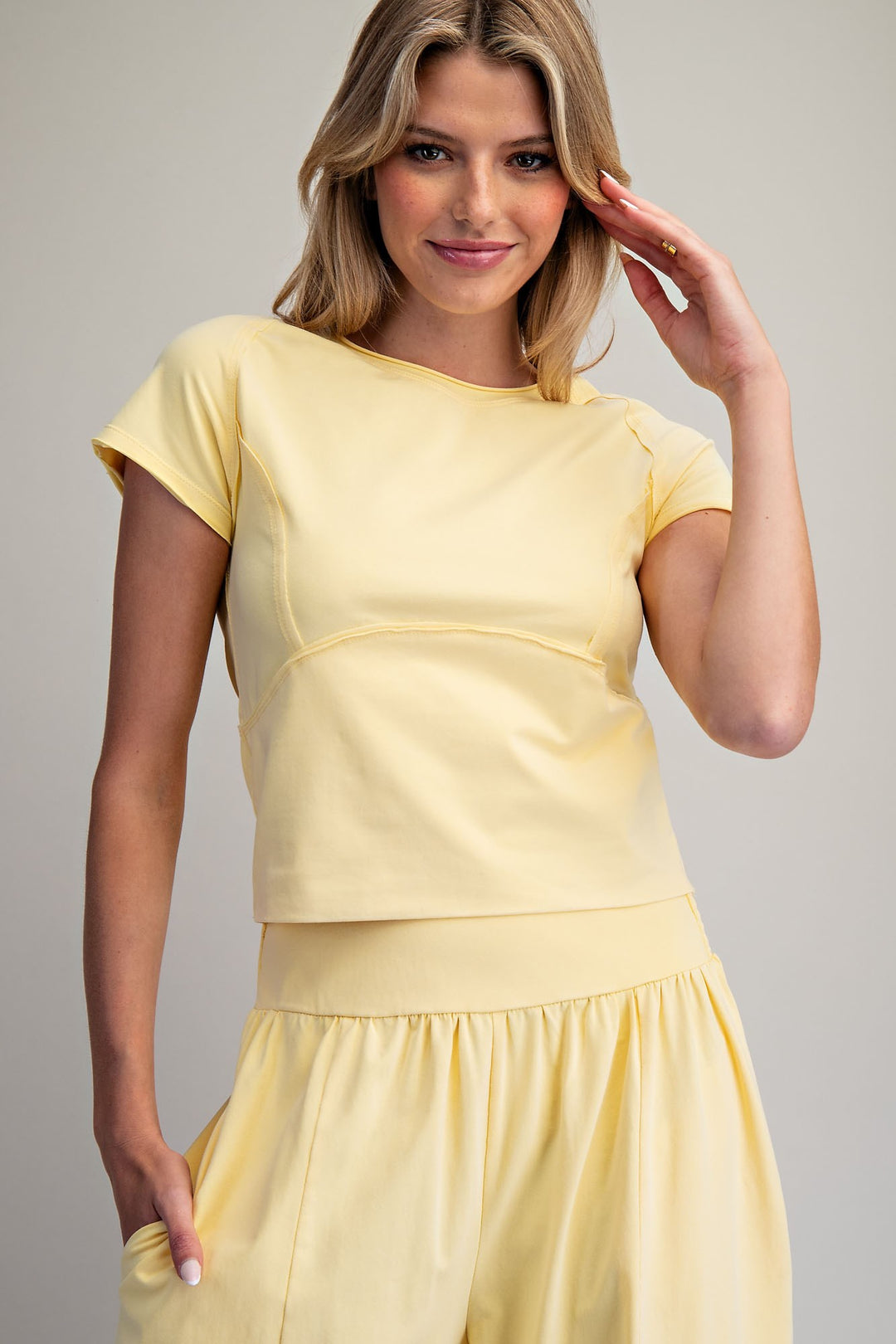Woman wearing a yellow matching set against a plain background