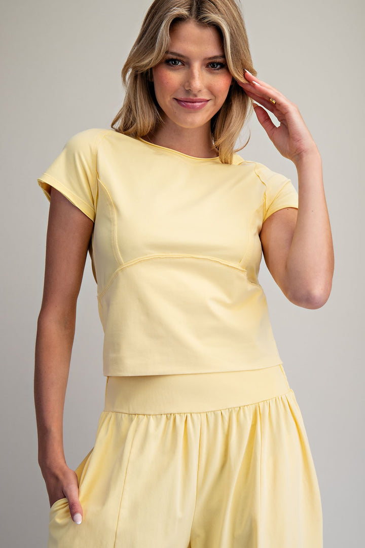 Woman wearing a yellow matching set against a plain background