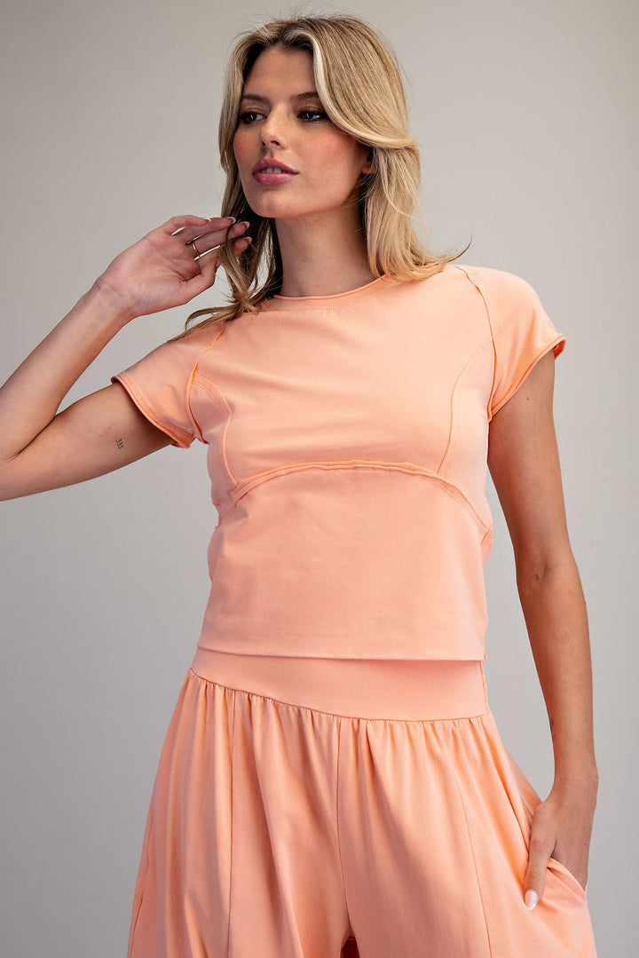 Woman wearing a peach-colored outfit against a plain background