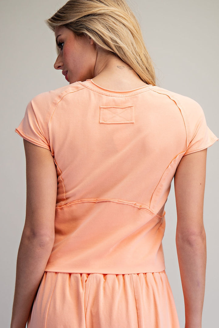 Woman wearing a peach-colored matching set against a plain background