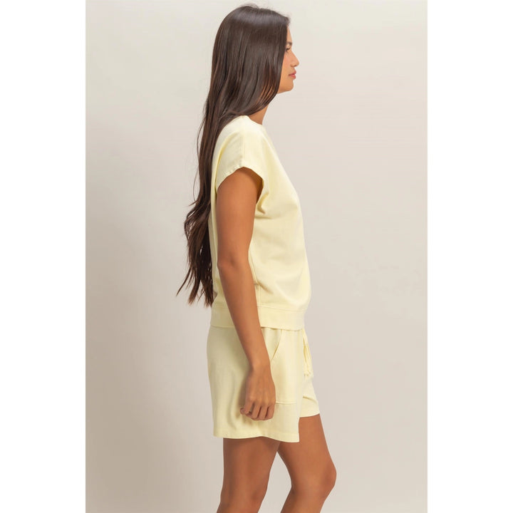 Woman wearing a light yellow outfit against a plain background