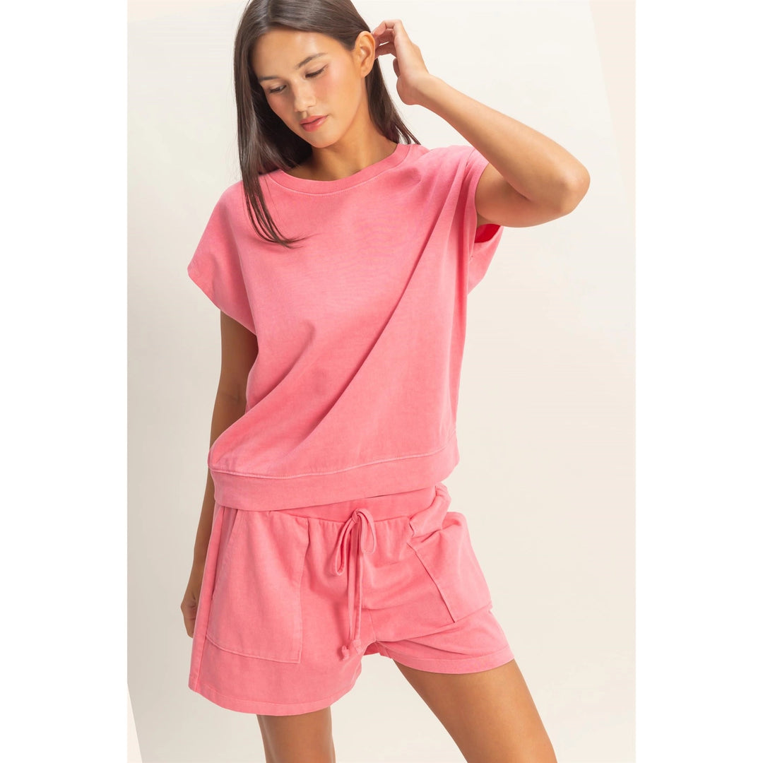 Woman wearing a pink lounge set on a plain background